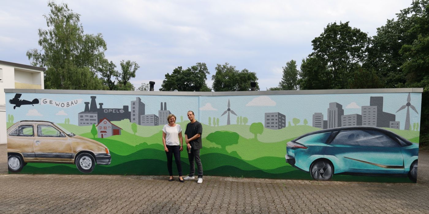 gewobau Prokuristin und Leiterin der Abteilung Wohnungswirtschaft Anke Luciano und Künstler Oliver Pusch alias „Blazin Vibes“ vor der Graffiti Garage am Hessenring 80