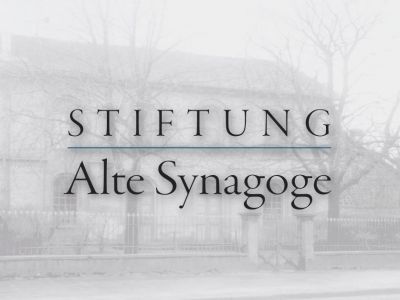 Im Hindergrund die Alte Synagoge in Rüsselsheim mit dem Logo der Stiftung im Vordergrund