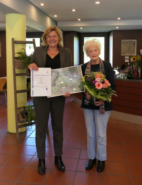 Anke Luciano ehrt Gerda Grüll für ihr Engagement im Vorgarten der Hausgemeinschaft