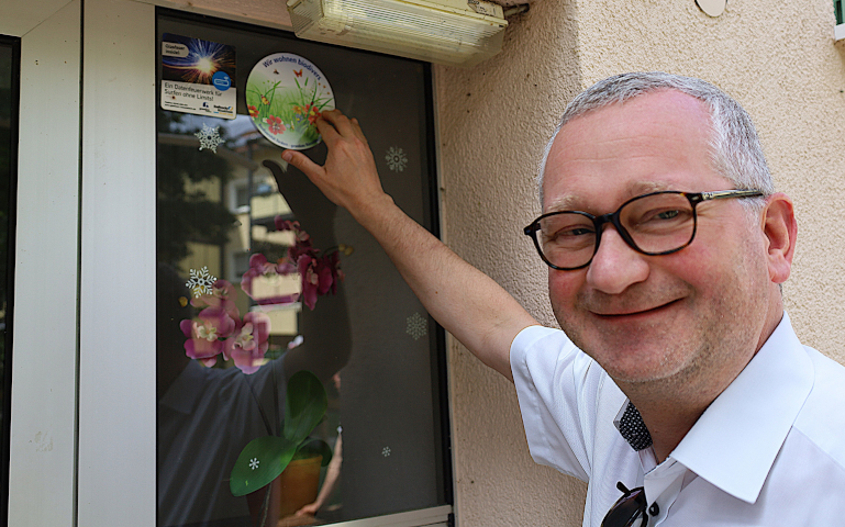 Geschäftsführer Torsten Regenstein bringt den Aufkleber für die biodiverse Außenanlage an