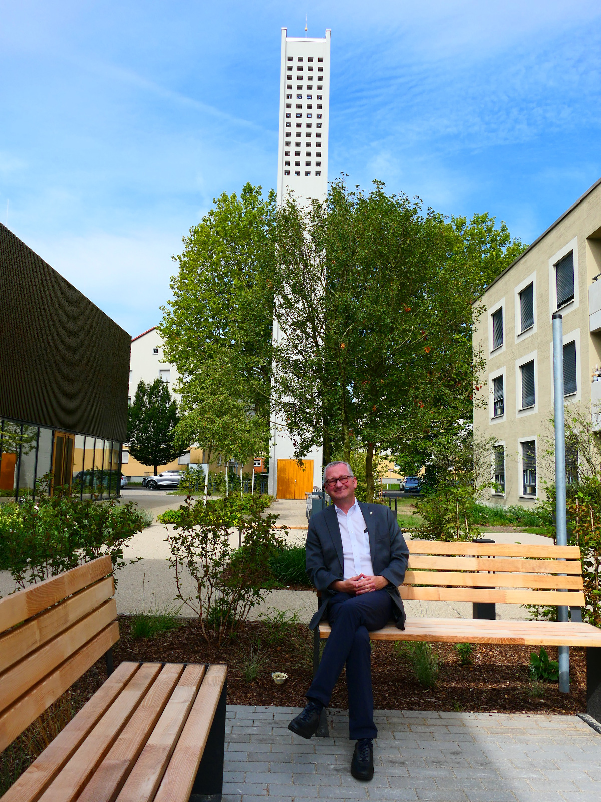 Torsten Regenstein sitzt auf der neuen Bank im neue angelegten Außenbereich