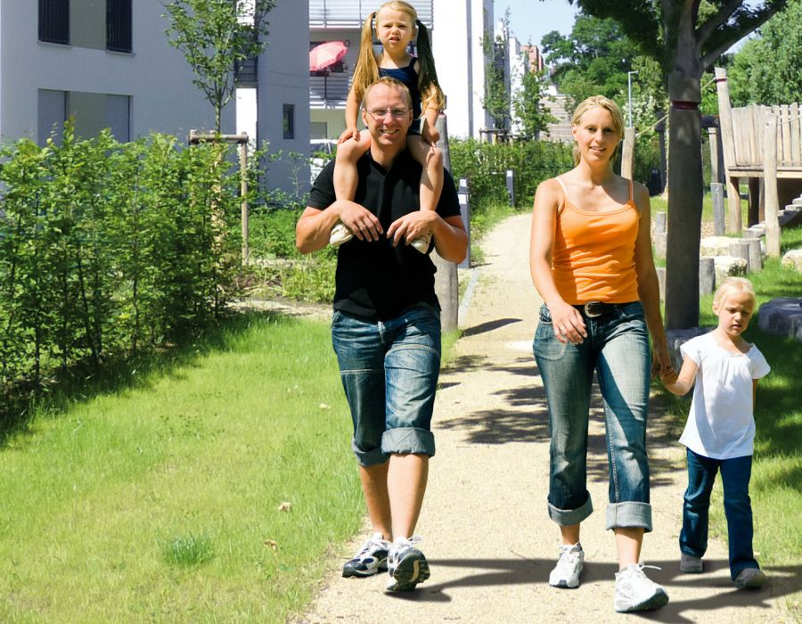 Bild einer glücklichen Famile, die im Grünen des Horlache Parks spazieren geht