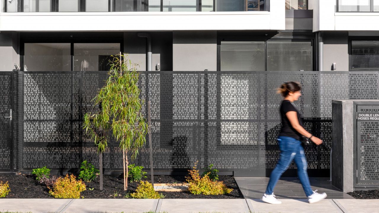 Bild einer Frau, die an einer Hausanlage entlang läuft