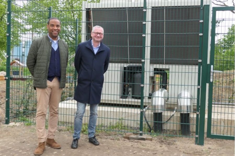 Lian Moiba und Torsten Regenstein sehen vor den neuen Luft-Wärmepumpen der Wohnanlage Hasengrund 72