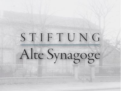 Im Hindergrund die Alte Synagoge in Rüsselsheim mit dem Logo der Stiftung im Vordergrund