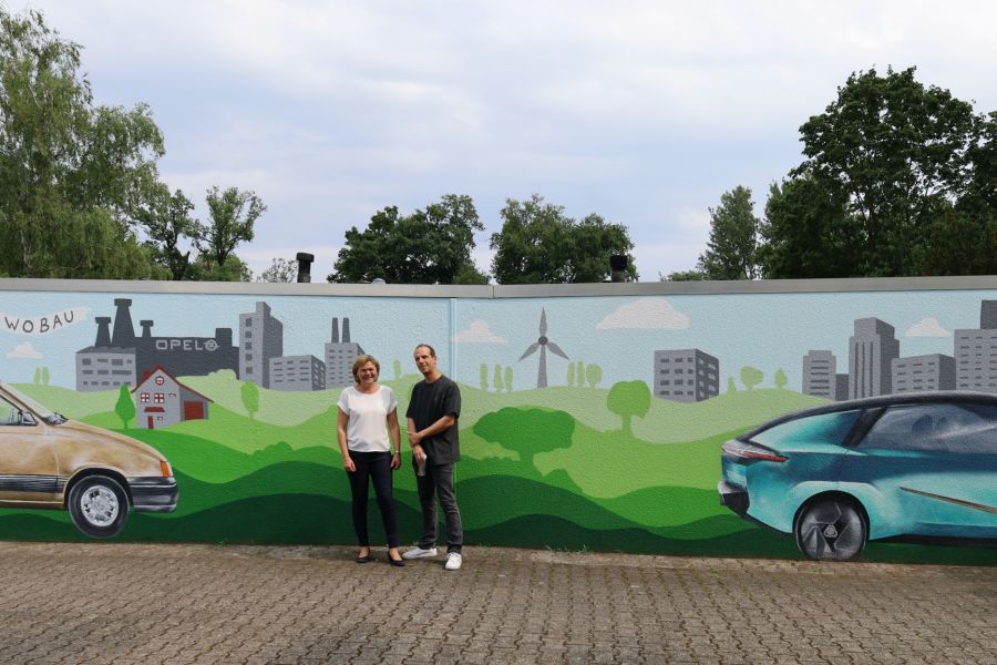 gewobau Prokuristin und Leiterin der Abteilung Wohnungswirtschaft Anke Luciano und Künstler Oliver Pusch alias „Blazin Vibes“ vor der Graffiti Garage am Hessenring 80