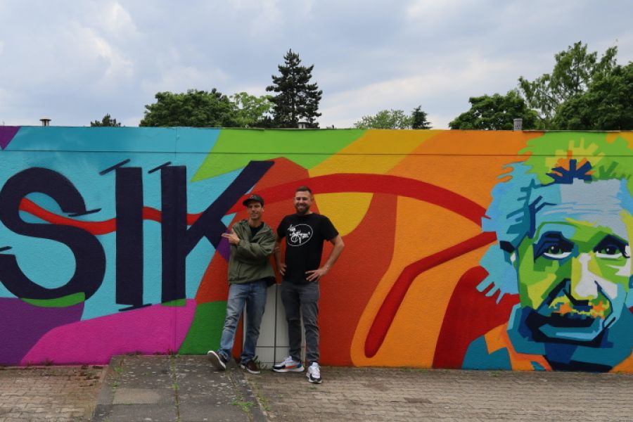 Die Künster stehen vor der neu gestalteten Graffiti Garagenwand in der Liebigstraße 20