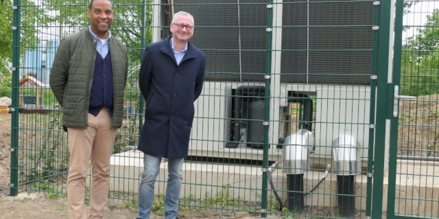 Lian Moiba und Torsten Regenstein sehen vor den neuen Luft-Wärmepumpen der Wohnanlage Hasengrund 72