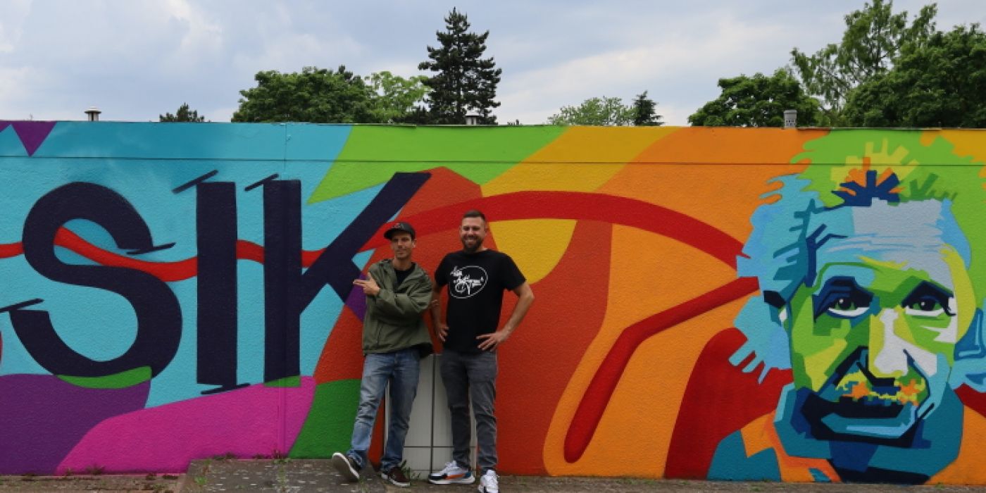 Die Künster stehen vor der neu gestalteten Graffiti Garagenwand in der Liebigstraße 20